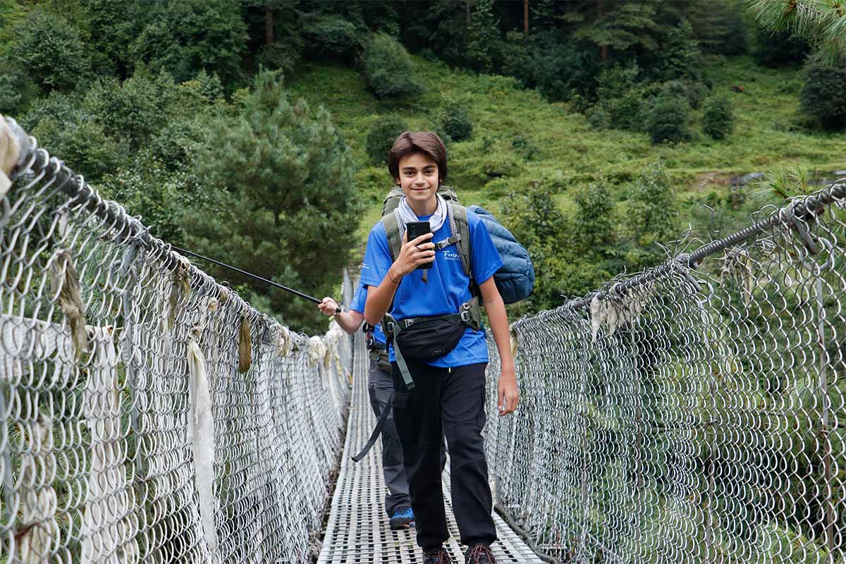 Young hiker crossing suspension bridge on EBC trek